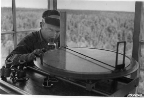 Mr. Burr Webb, lookout at Promontory tower, sights through the Osborne fire-finder (1939)